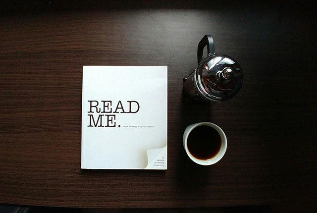 A book titled 'Read Me' next to a cup of coffee